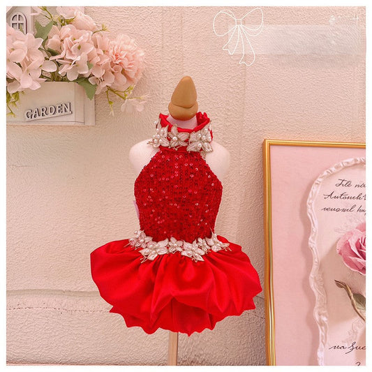 Red dress with floral details on a mannequin against a decorative wall.