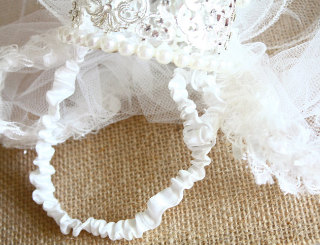 White lace headband with intricate details on a textured beige background