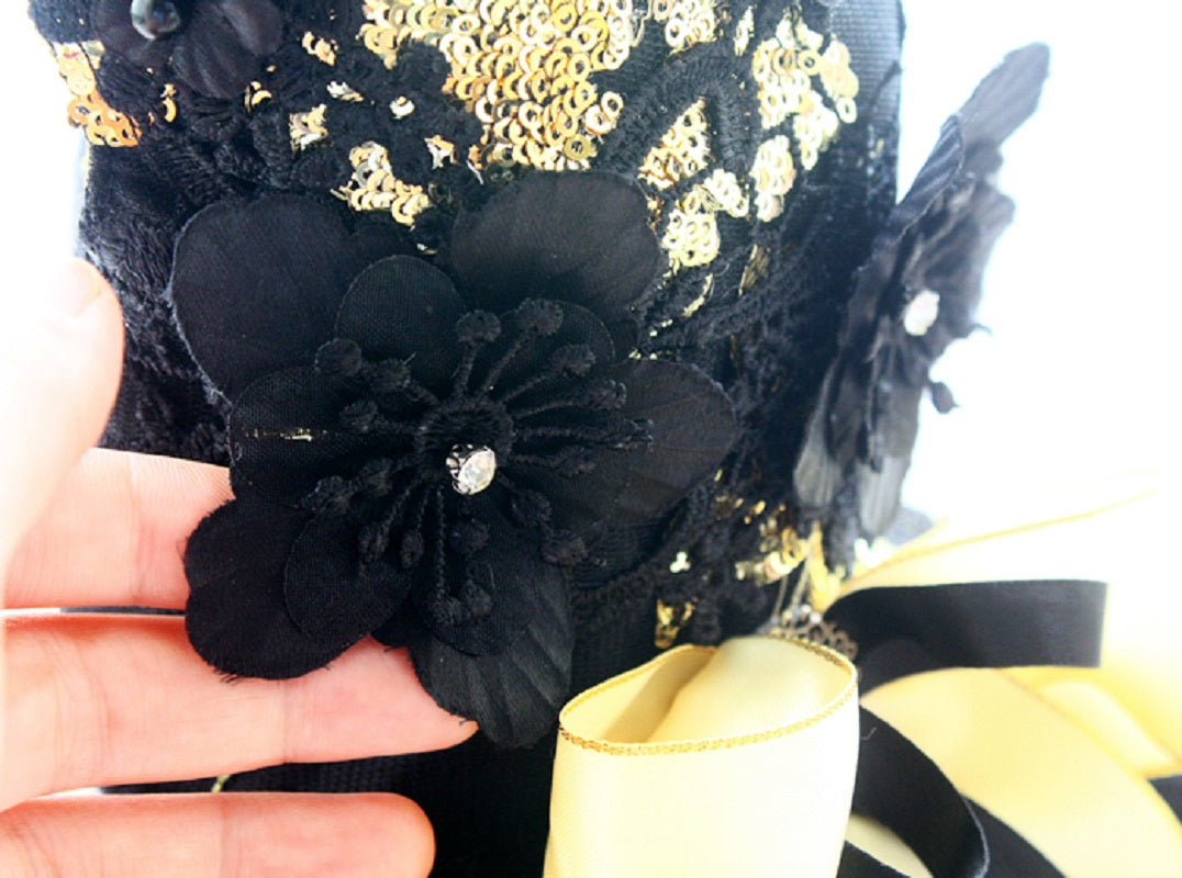 Black floral embellishment on a black and gold dress with a yellow bow.