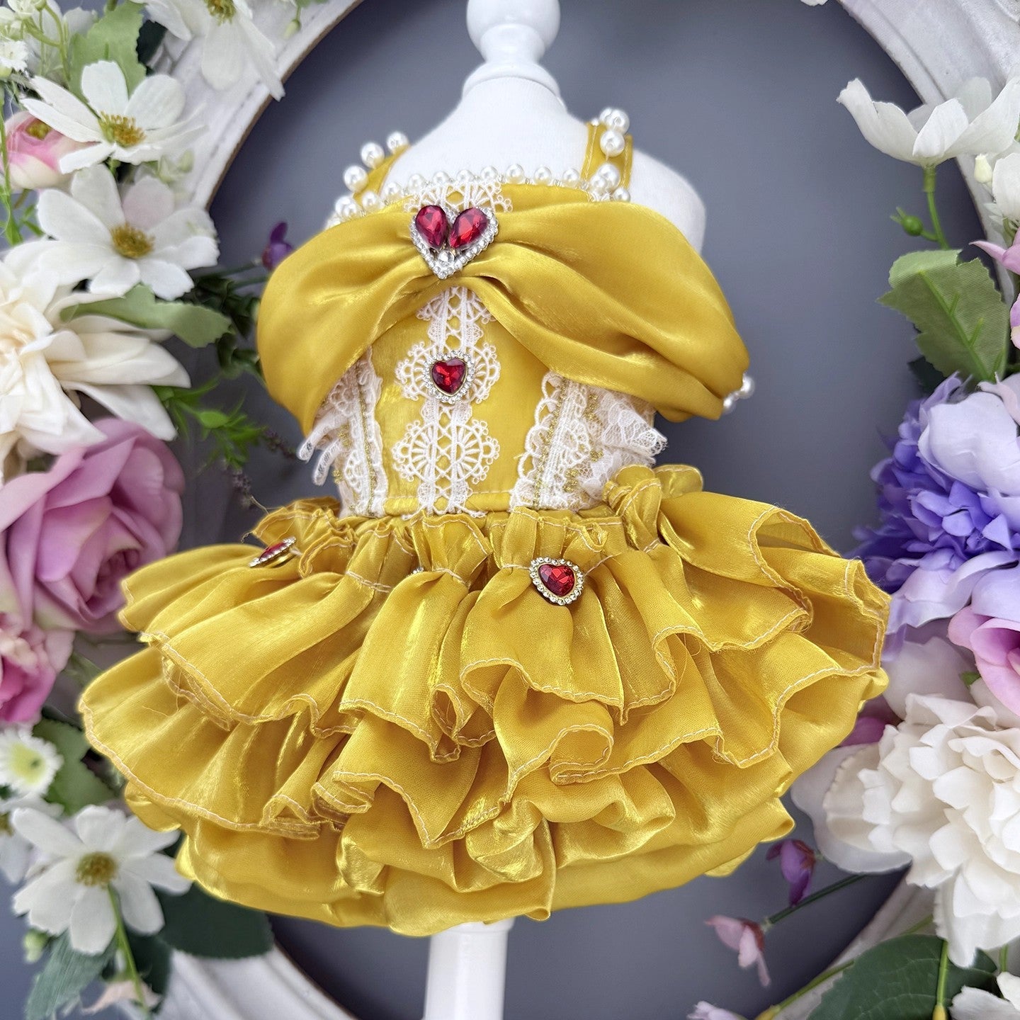 Yellow dress with red heart details on a mannequin surrounded by flowers