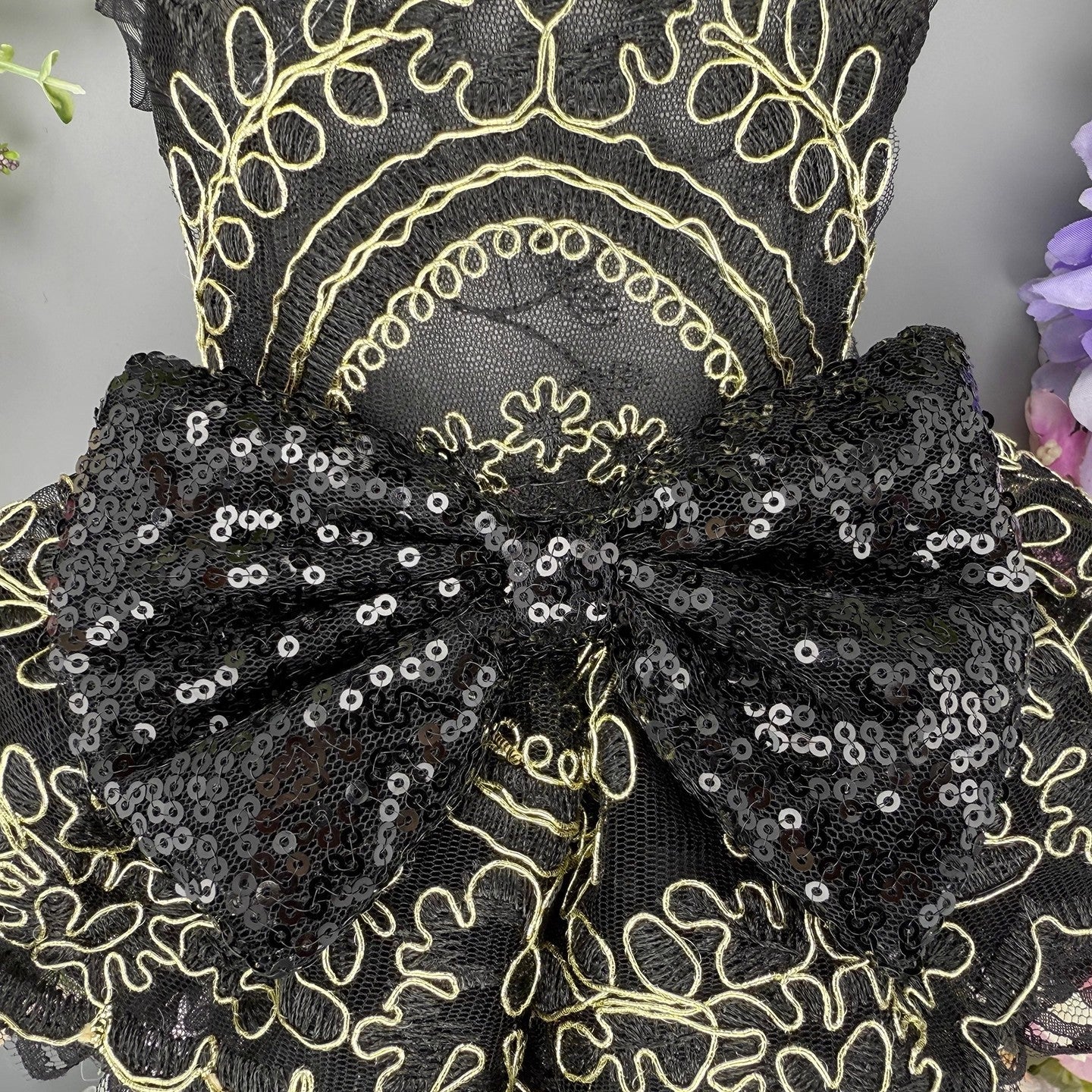 Black lace fabric with gold embroidery and sequin details on a mannequin.