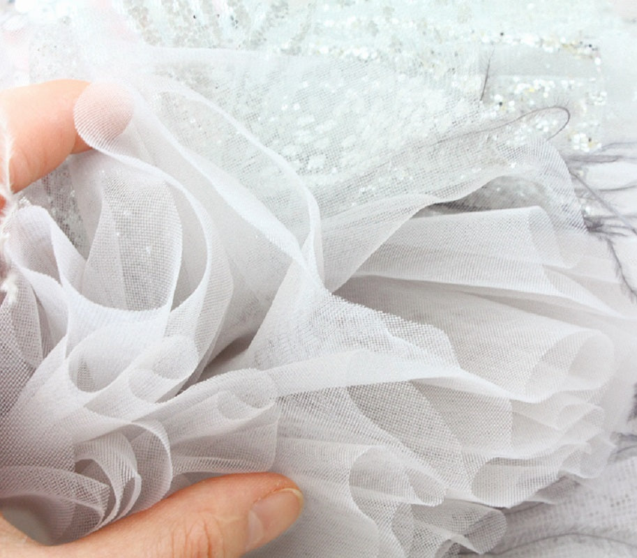 Close-up of white tulle fabric held by a hand