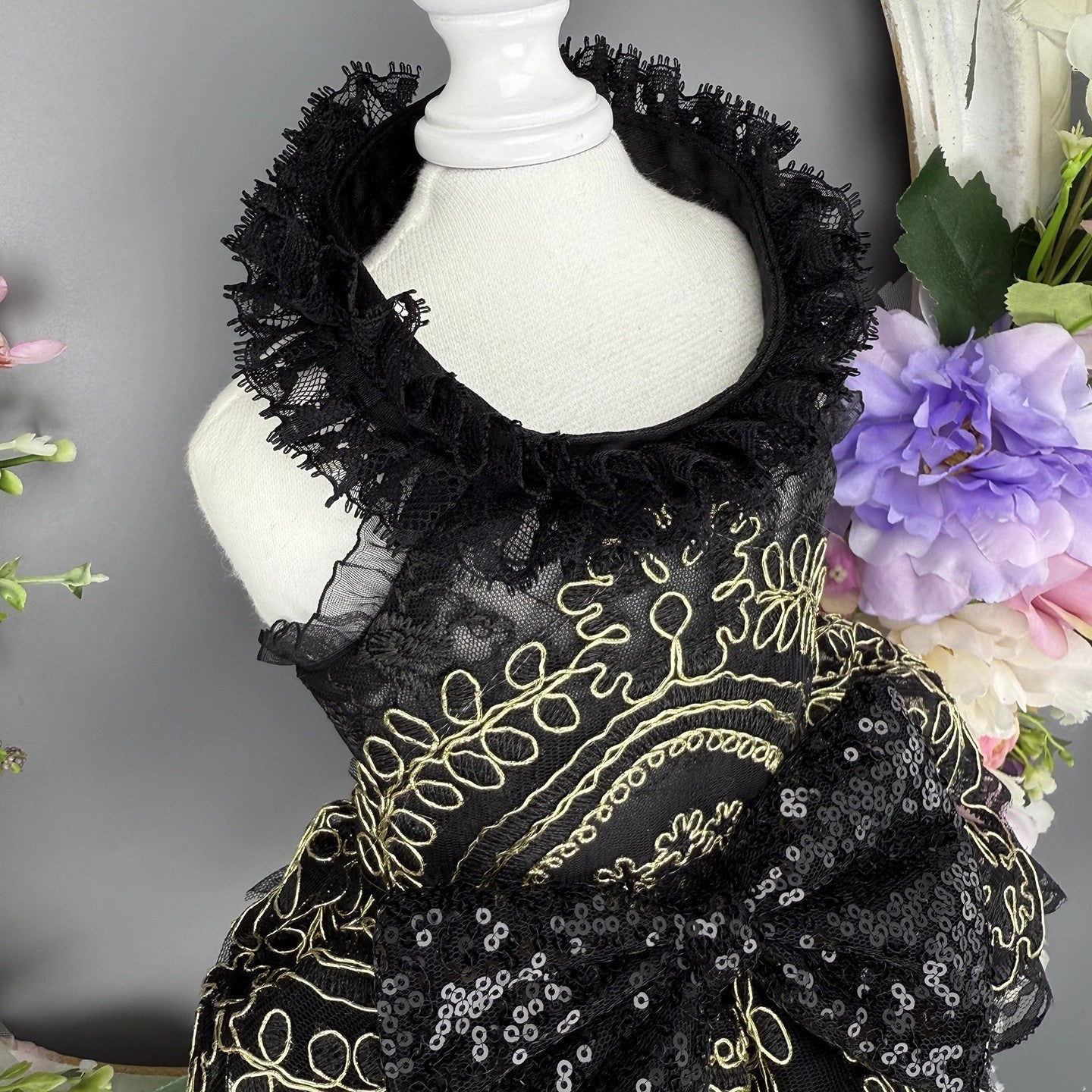 Black embroidered dress on a mannequin with flowers in the background