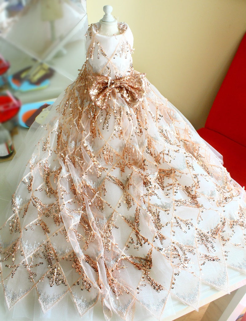 White dress with rose gold embellishments on a mannequin against a blurred indoor background