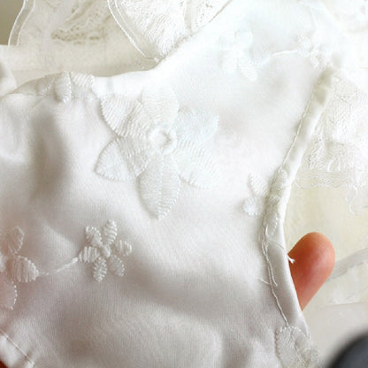 Close-up of white embroidered fabric with a hand holding it