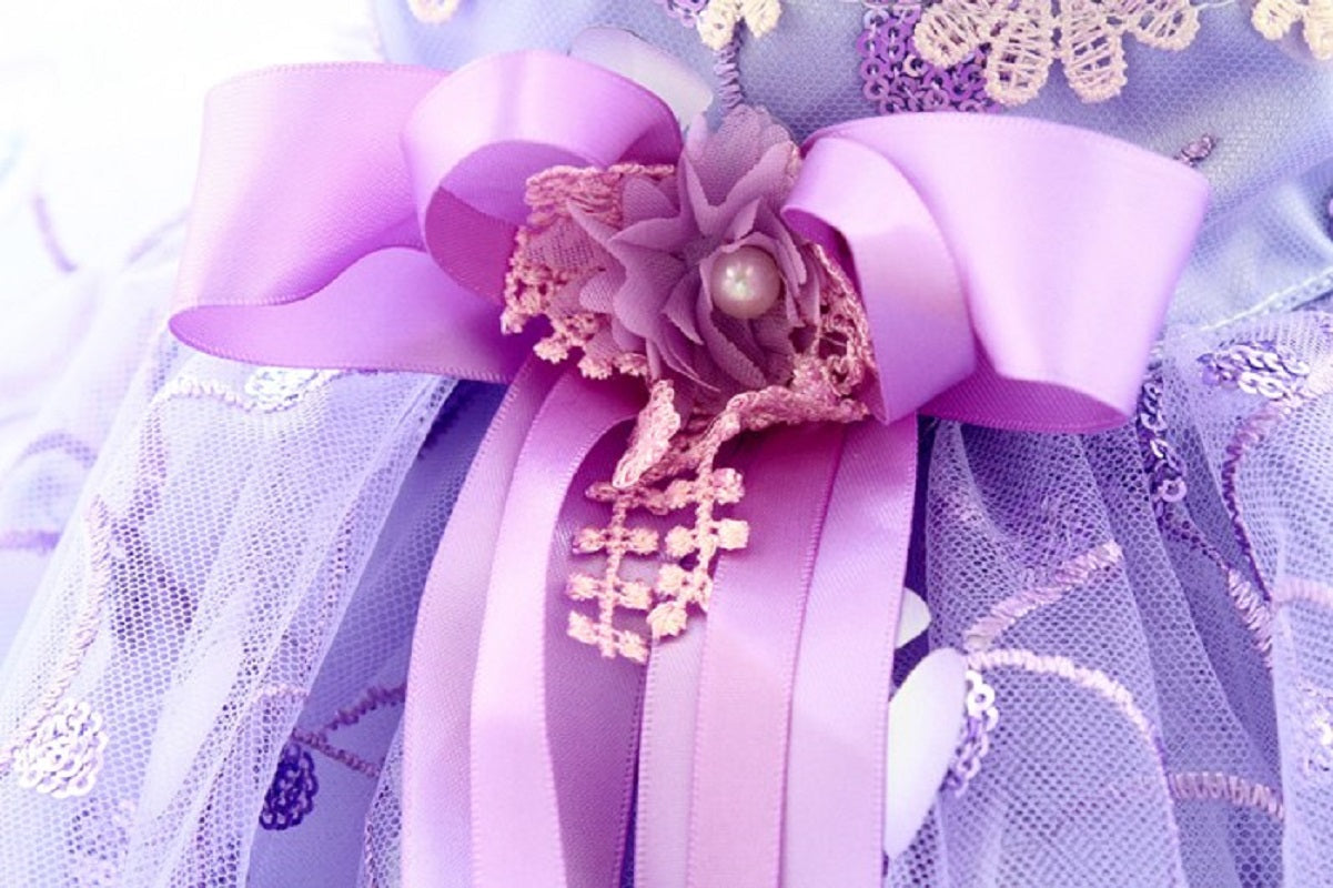 Decorative bow with floral elements and pearls on a light purple background