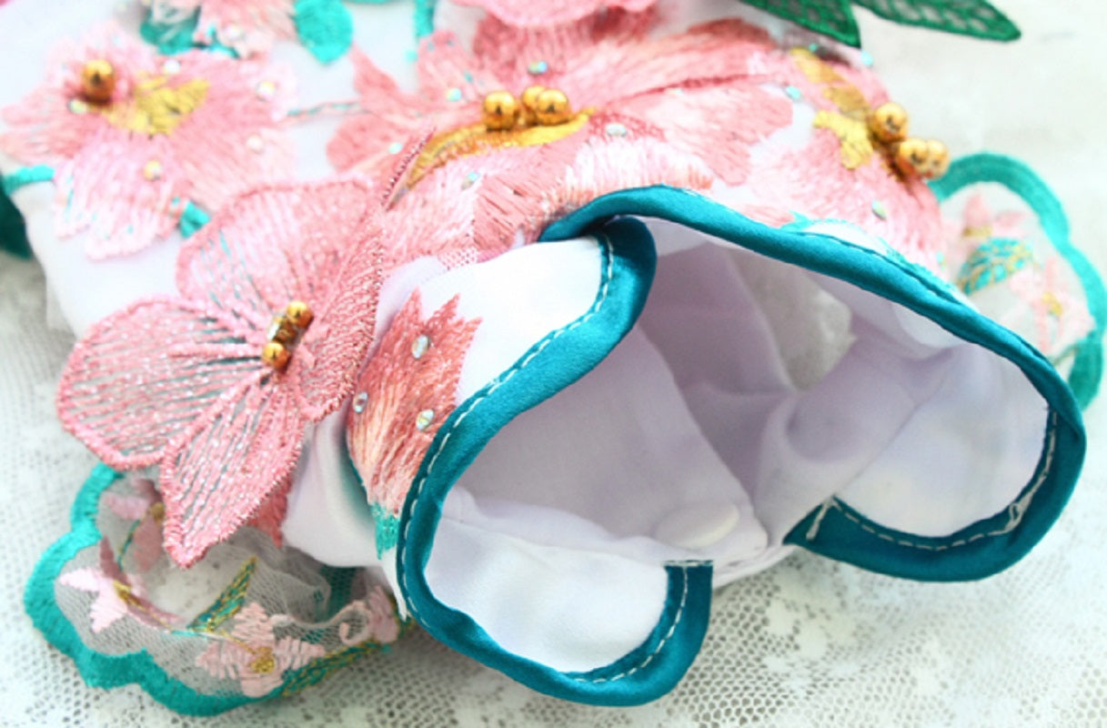 Decorative headband with pink flowers and teal accents on a light background