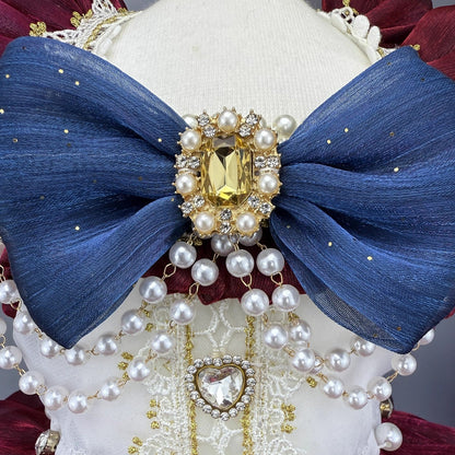 Decorative headpiece with blue bow, pearls, and gold accents on a white background