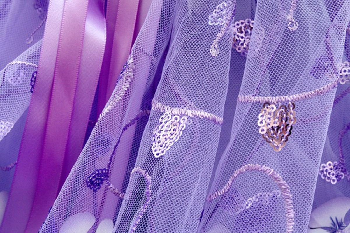 Close-up of purple fabric with floral embroidery and ribbons
