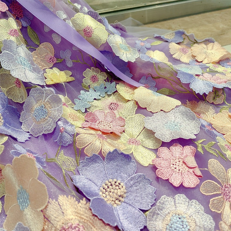 Floral embroidery fabric with colorful flowers on a purple background