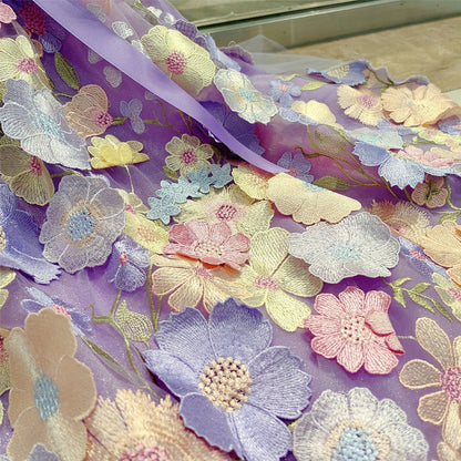 Floral embroidery fabric with colorful flowers on a purple background