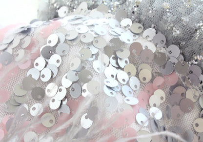 Close-up of silver sequins on a textured fabric background