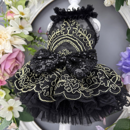 Black lace dress with gold embroidery on a mannequin surrounded by flowers