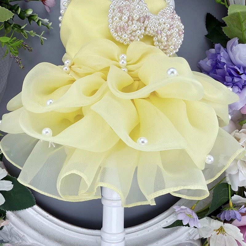 Yellow flower arrangement with pearls on a decorative stand.