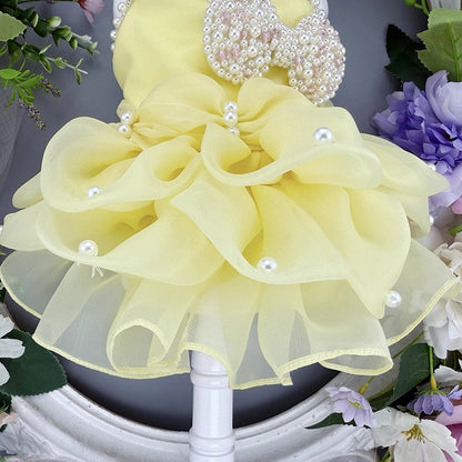 Yellow flower arrangement with pearls on a decorative stand.