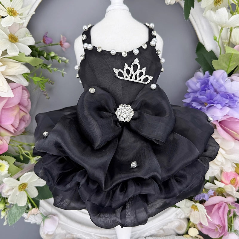 Black pet dress with a large bow and tiara on a mannequin against a floral background
