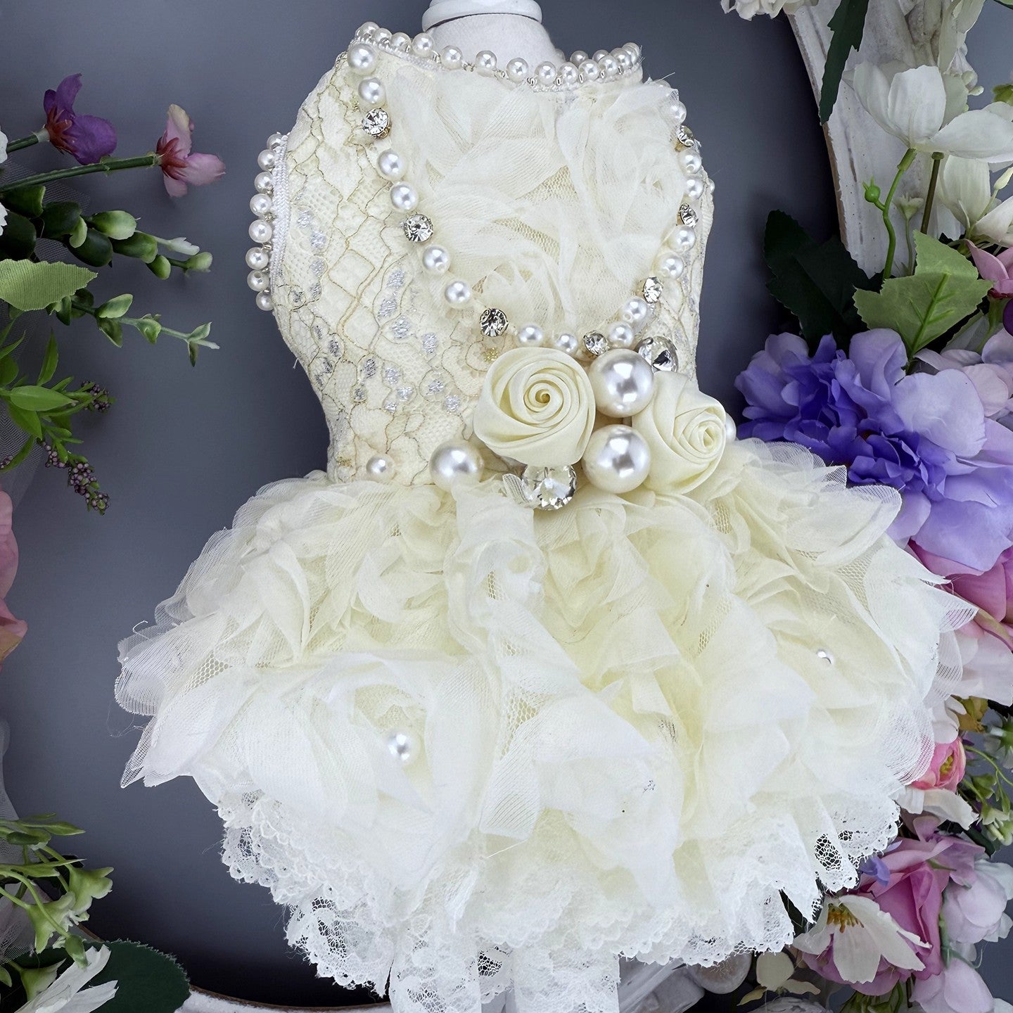 White floral dress with pearls on a mannequin against a floral background