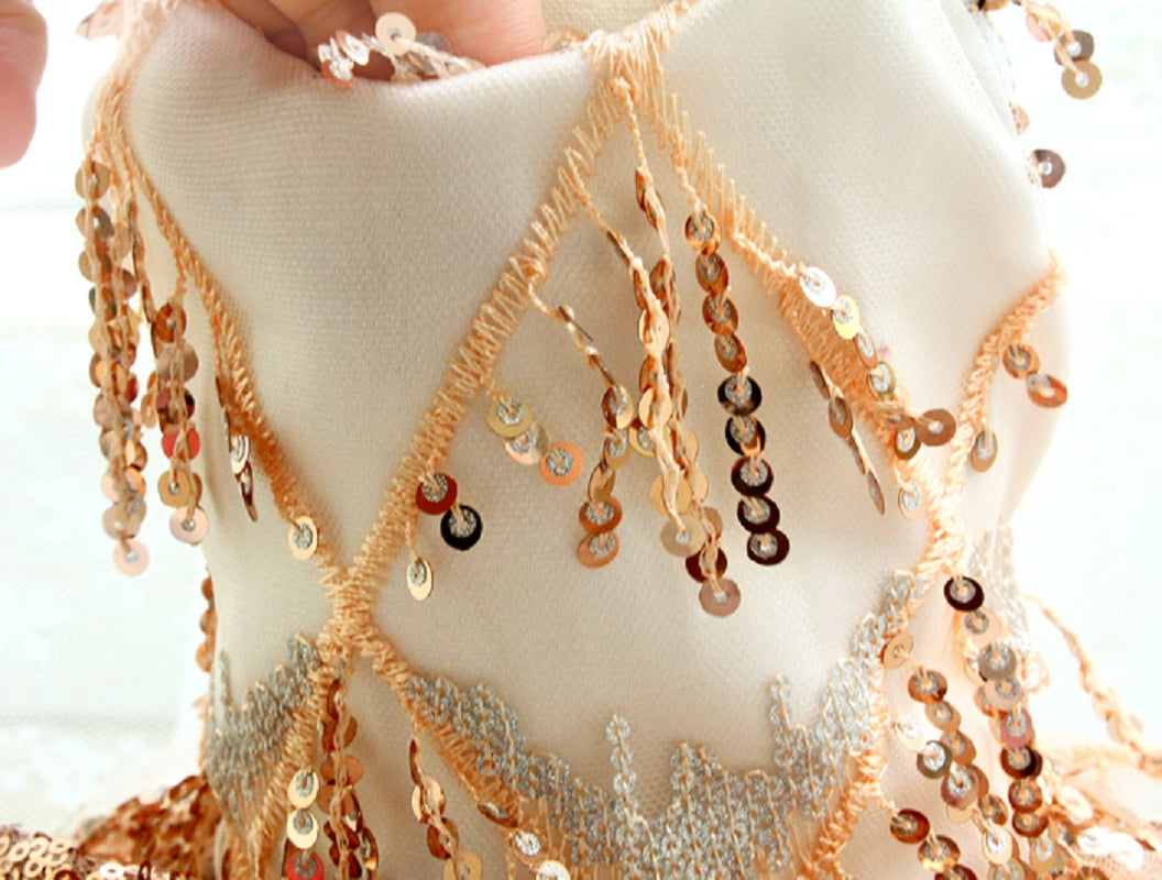 Close-up of a person wearing a white garment with gold and silver bead embellishments.