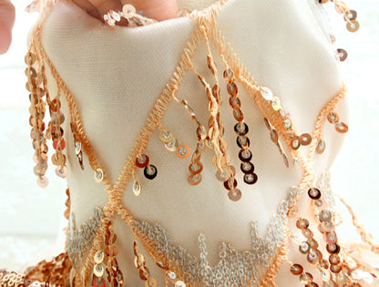 Close-up of a person wearing a white garment with gold and silver bead embellishments.