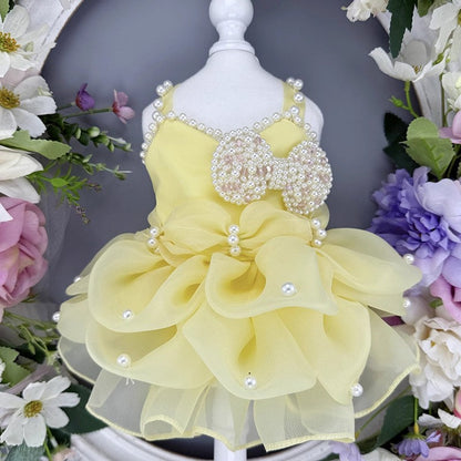 Yellow pet dress with floral details on a mannequin surrounded by flowers