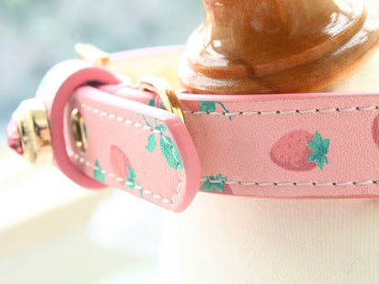 Pink dog collar with strawberry pattern on a blurred background