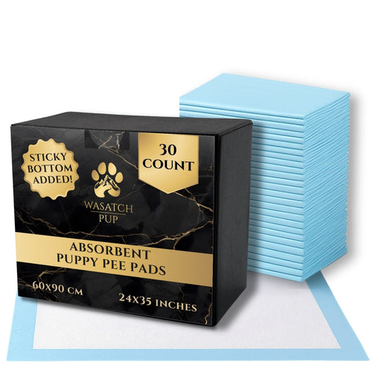 Box of Wasatch Pup absorbent puppy pee pads with a stack of blue pads on a white background.