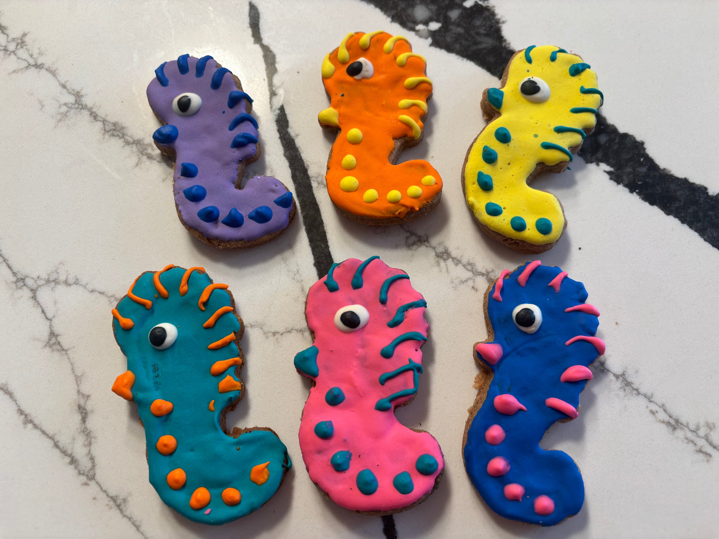 Colorful seahorse-shaped cookies on a marble surface