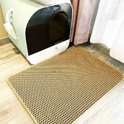 Cat litter box with a perforated mat on a wooden floor