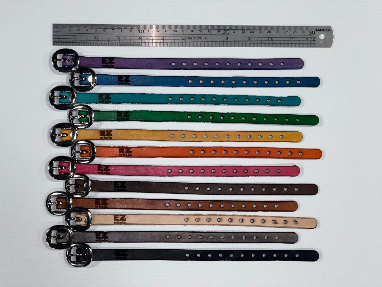 Colorful dog collars arranged in a row with a ruler for size reference on a white background.