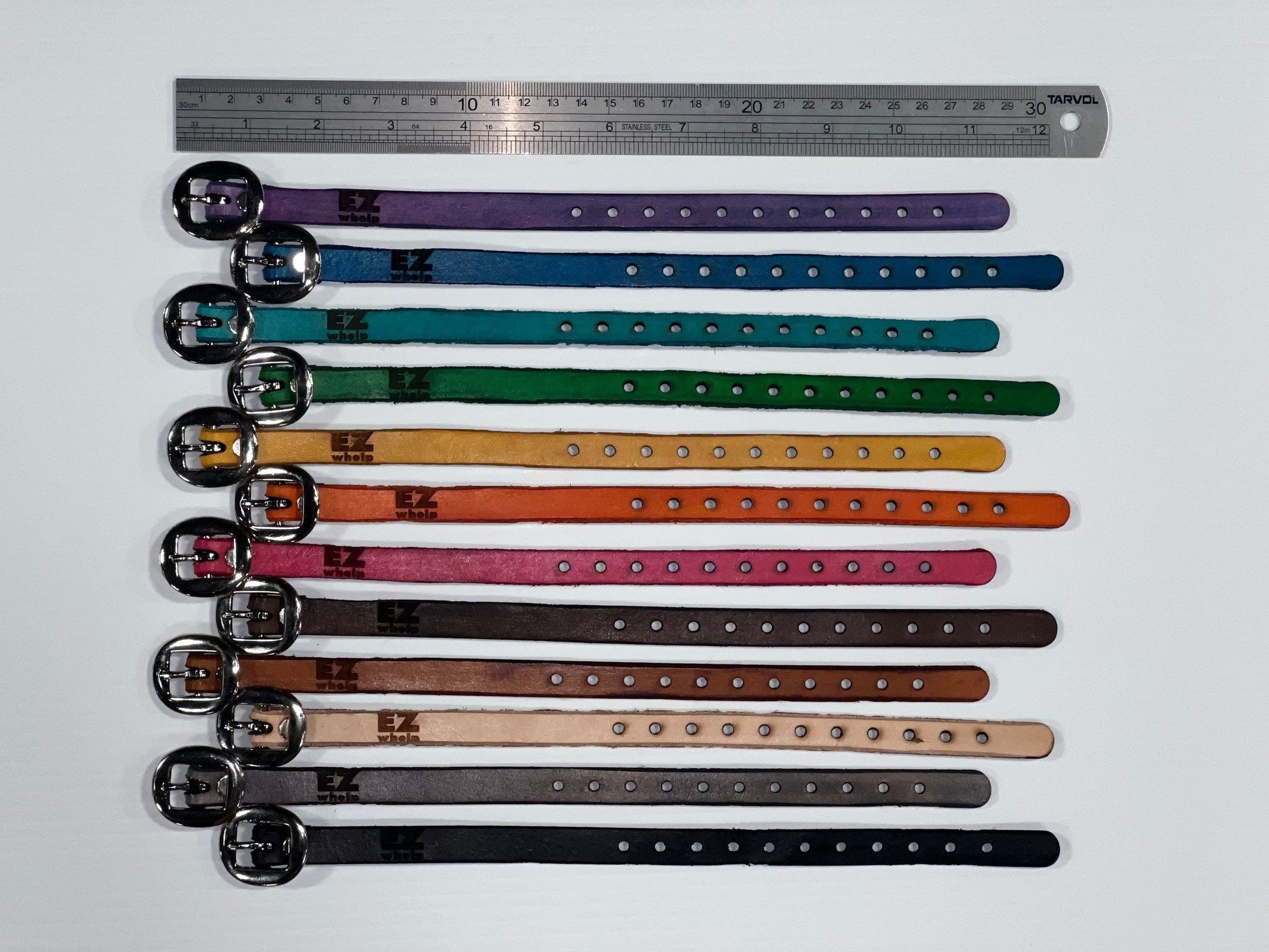 Colorful dog collars arranged in a row with a ruler for size reference on a white background.
