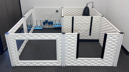 White pet playpen with transparent gate on a gray floor against a white wall.