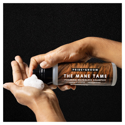 Hand holding a bottle of 'The Mane Tame' shampoo with a black background
