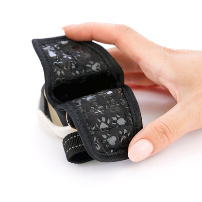 Black pet muzzle with floral pattern held by a hand on a white background