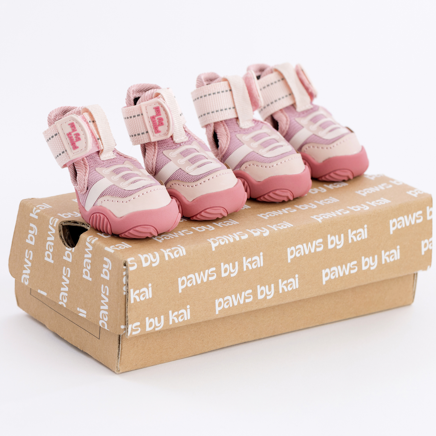 Pink pet shoes on a 'paws by kai' branded box against a white background