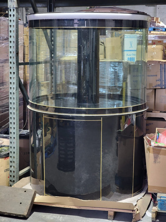 Round glass display case with gold trim in a warehouse setting