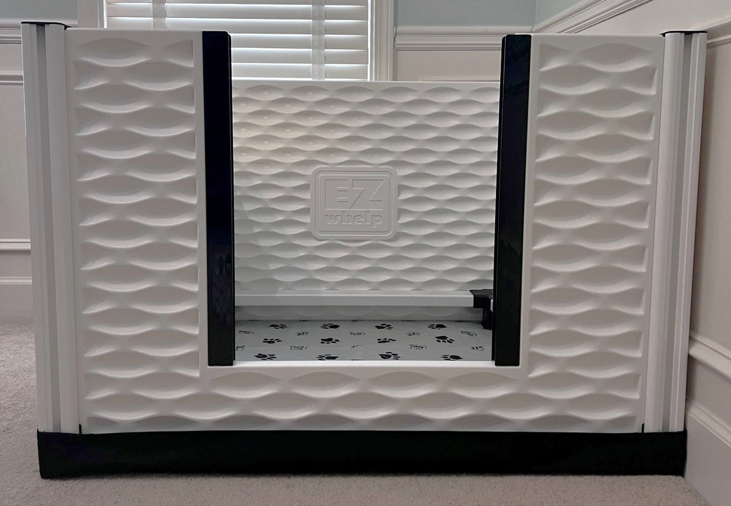 White pet gate with wavy pattern and 'EZ' logo in a room setting.