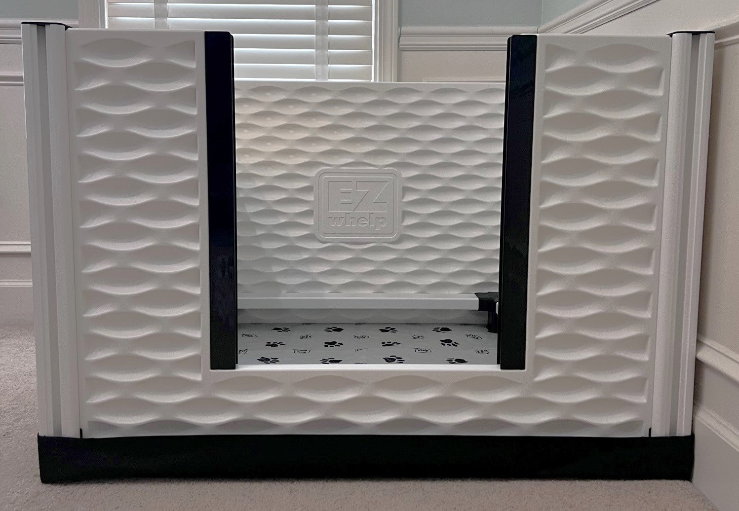 White pet gate with wavy pattern and 'EZ' logo in a room setting.