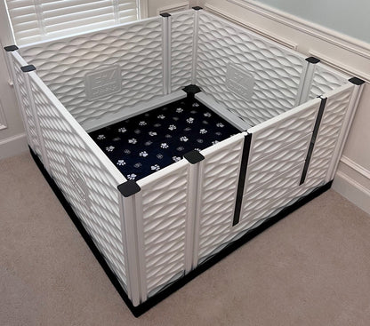 White pet playpen with a black mat inside on a carpeted floor.