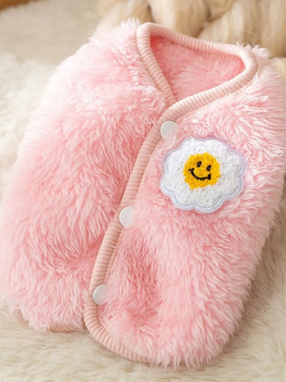 Pink fluffy slippers with a smiley face design on a soft surface