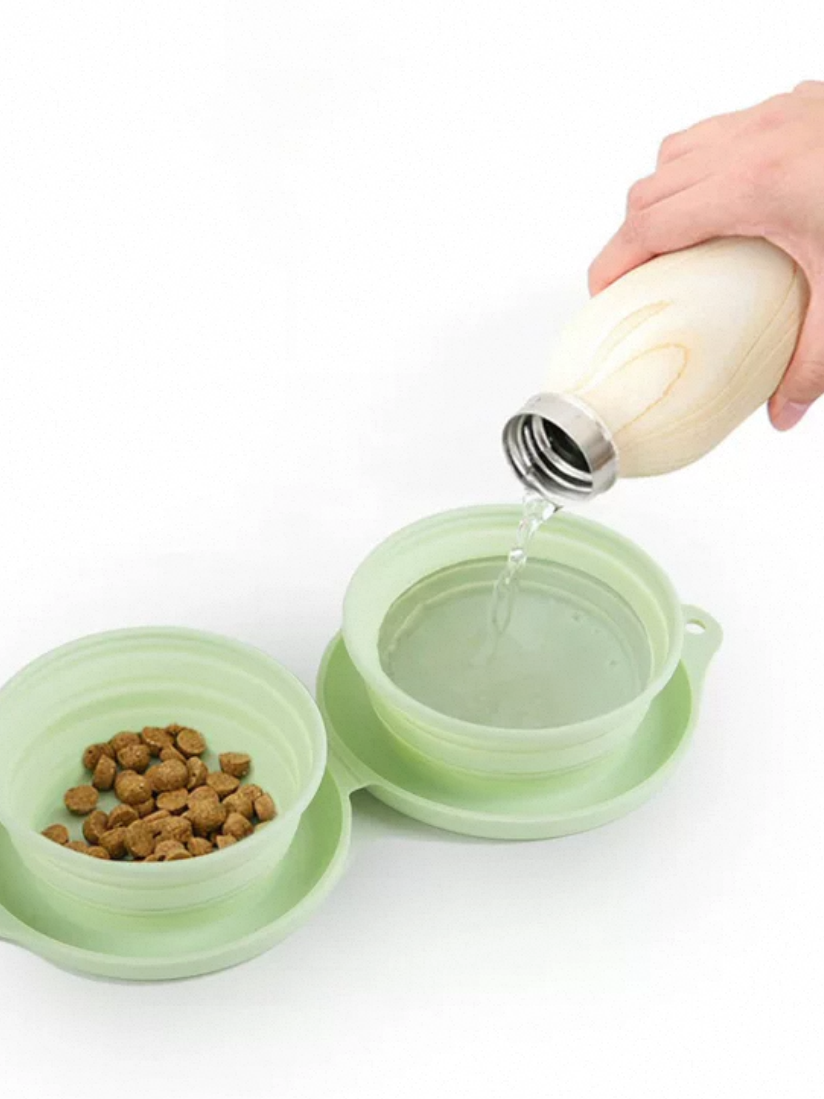 Green pet bowl with food and water, being filled with a bottle on a white background