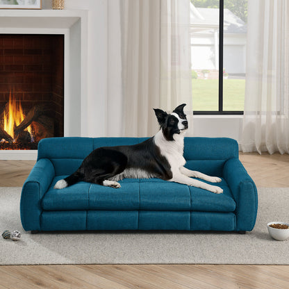Dog lying on a blue pet sofa in a living room with a fireplace and large window.