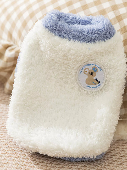 White fuzzy bottle cover with blue rim and a logo on a textured surface