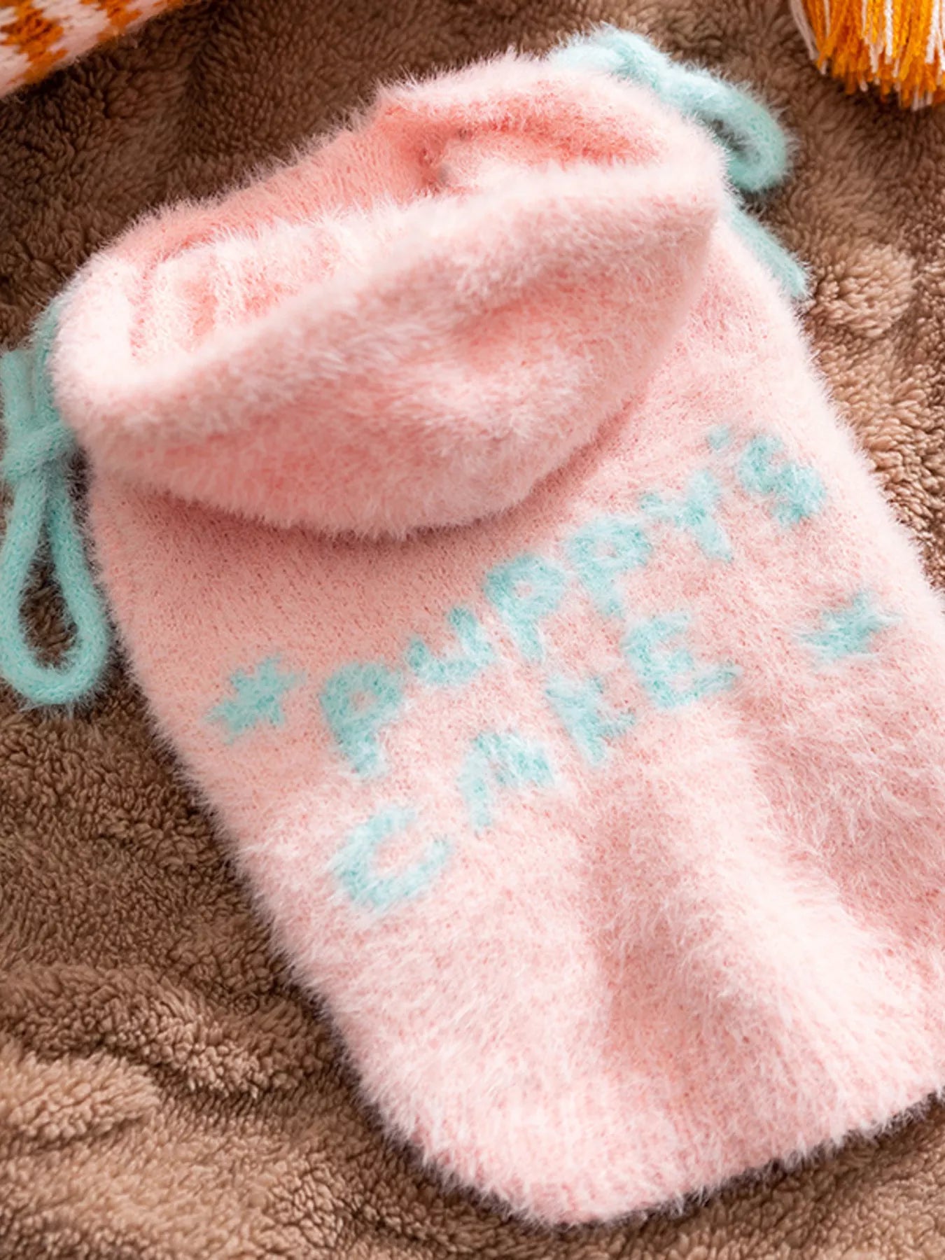 Pink plush drawstring bag with 'Puppies Cake' text on a brown textured surface
