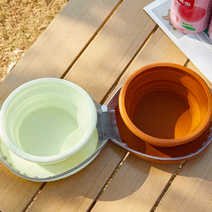 Two collapsible bowls, one green and one orange, on a wooden surface.