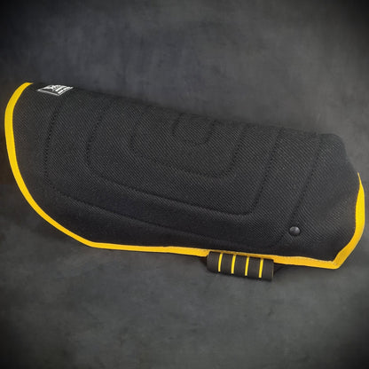 Black motorcycle seat cover with yellow trim on a dark background