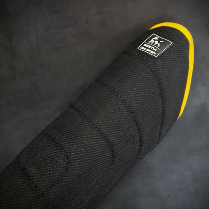 Close-up of a black car seat cover with a yellow edge and a brand logo on a dark background.