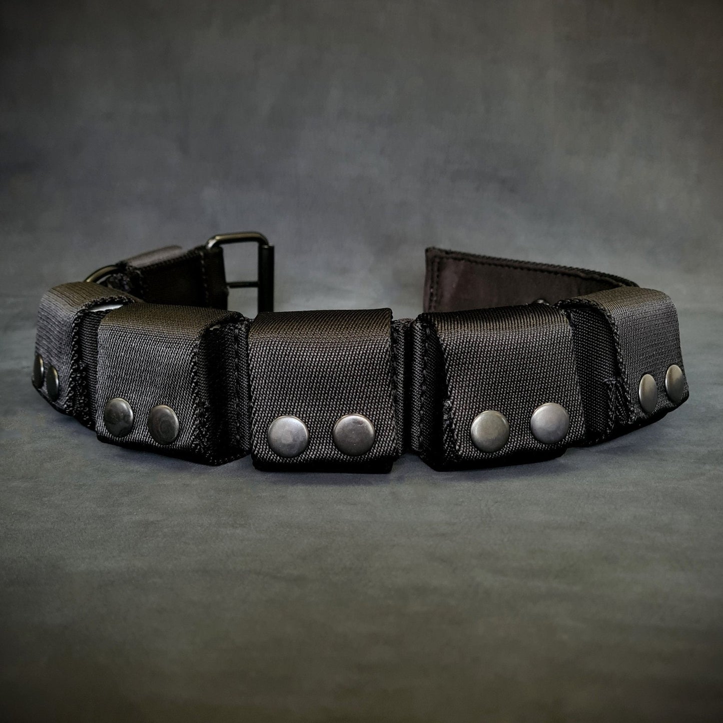 Black leather belt with silver studs on a gray background