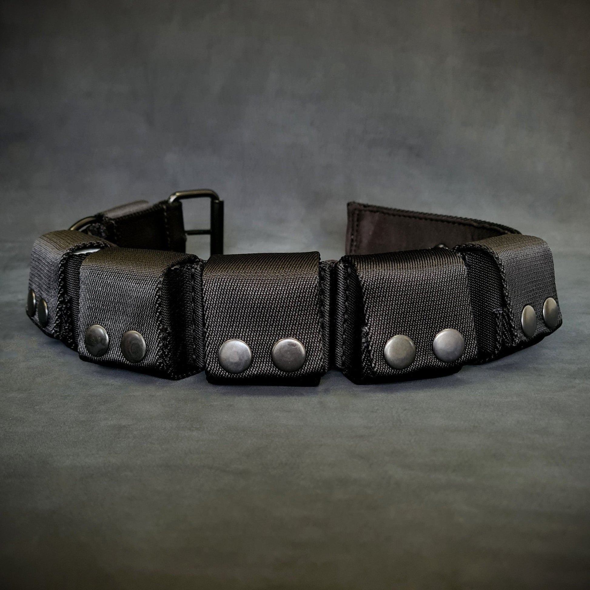 Black leather belt with silver studs on a gray background