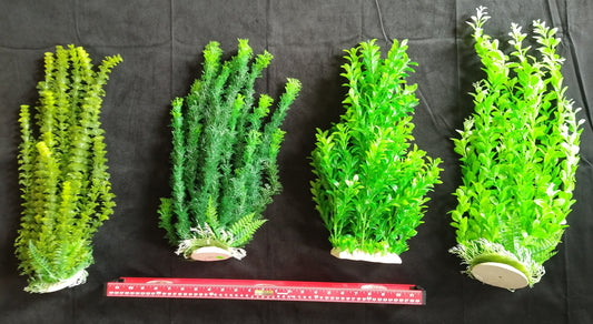 Four pieces of green artificial plants on a black background with a ruler for scale.