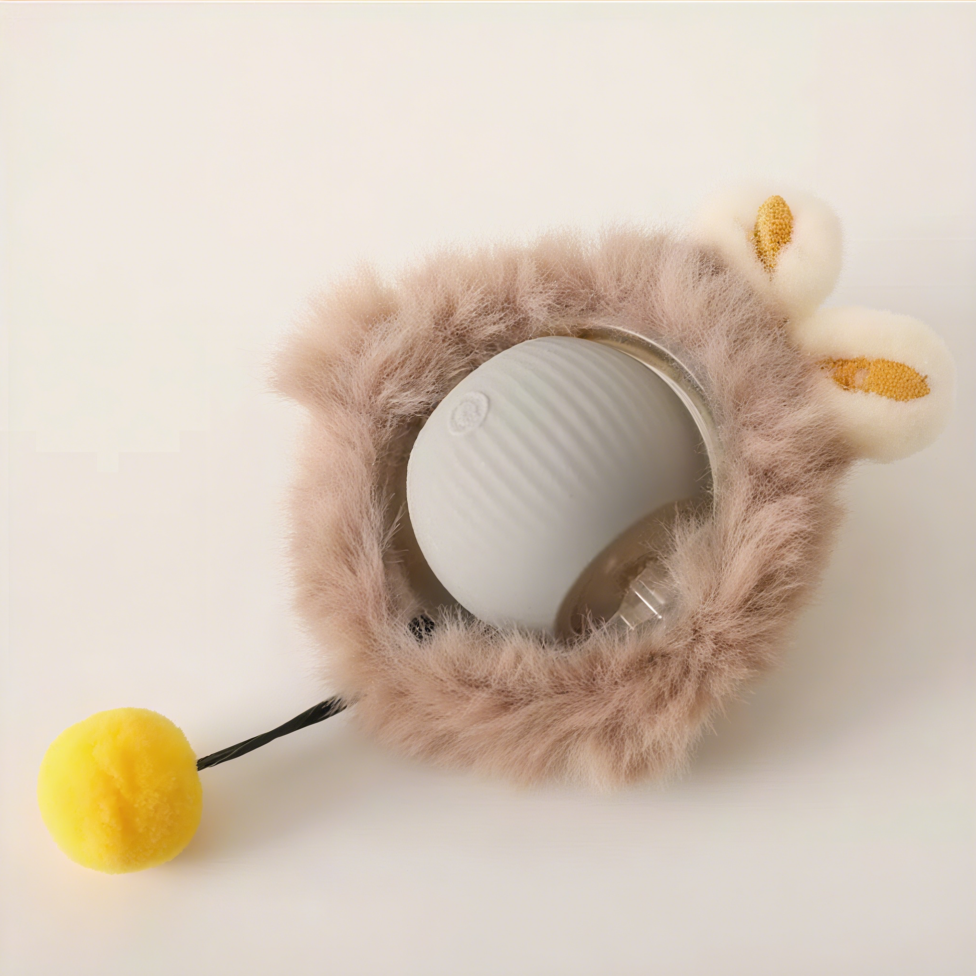 White ball with fluffy brown holder and yellow pom-pom on a light background